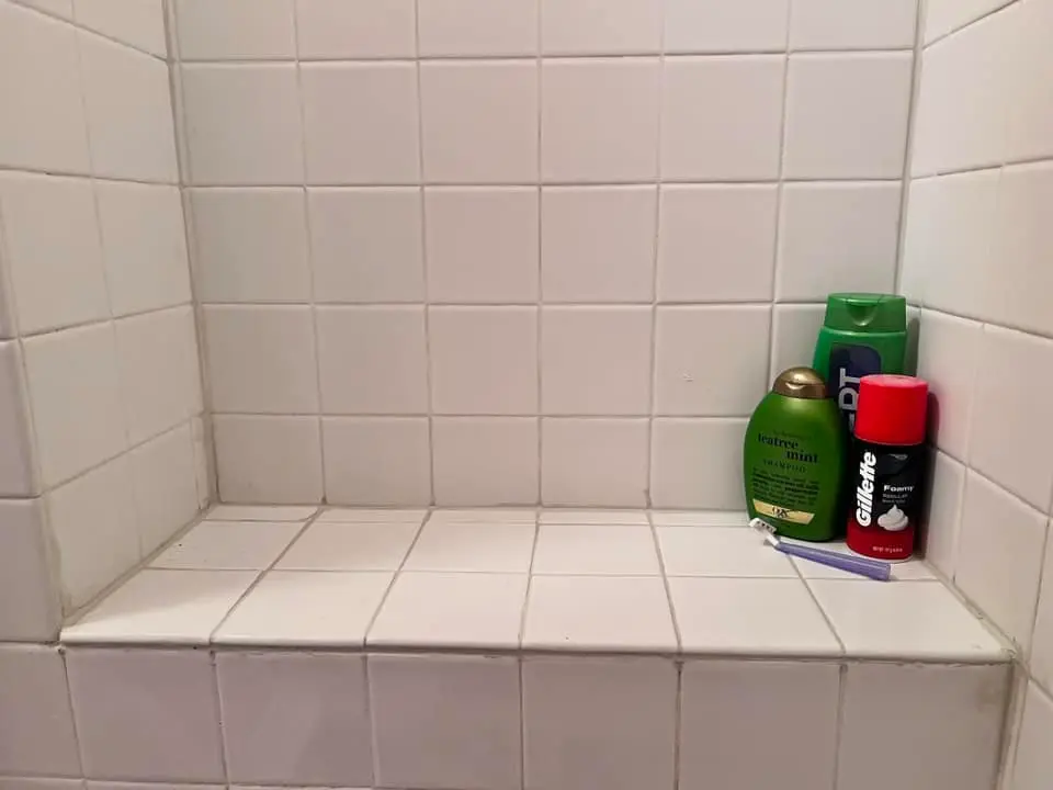Shower bench retiled in white square tile with fresh grout